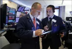  ?? Associated Press ?? Traders Michael Urkonis, left, and Tommy Kalikas confer in a booth on the floor of the New York Stock Exchange. Stocks took a nosedive and bond prices spiked after President Donald Trump said the U. S. would raise tariffs on more Chinese goods, increasing the stakes in an ongoing trade battle.