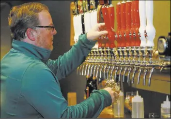  ?? Sue Ogrocki The Associated Press ?? Sean Mossman, director of sales and marketing for COOP Ale Works, draws a beer in the COOP taproom Friday in Oklahoma City. Grocery and convenienc­e stores in Oklahoma can now sell beer with more than 3.2 percent alcohol content.