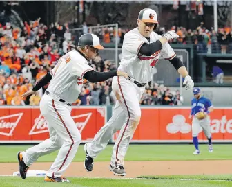  ??  ?? Orioles slugger Mark Trumbo celebrates with third base coach Bobby Dickerson after hitting a solo home run in the 11th inning against the Blue Jays in Baltimore on Monday.