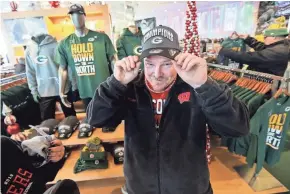  ?? MIKE DE SISTI / MILWAUKEE JOURNAL SENTINEL ?? Eric French of De Pere tries on a Green Bay Packers NFC North Division championsh­ip hat at the Packers Pro Shop on Monday at Lambeau Field in Green Bay. The baseball caps sold out by noon as fans celebrated making the playoffs.