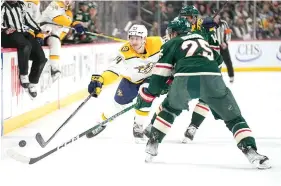  ?? (AP photo/Abbie Parr) ?? Nashville Predators left wing Tanner Jeannot, left, reaches for the puck next to Minnesota Wild defenseman Jonas Brodin (25) Feb. 19 during a hockey game in St. Paul, Minn.