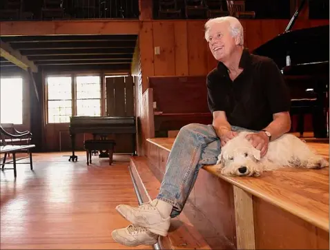  ?? Lori Van Buren / Times Union ?? Christian Steiner sits on the stage with his dog, Nikolai, by his side in the old barn at the Tannery Pond in New Lebanon in 2004. Steiner, a renowned portrait photograph­er who is especially popular with classical music artists, has announced his retirement from the summer series, which attracted many illustriou­s artists over the years.