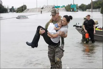  ?? AP PHOTO/DAVID J. PHILLIP ?? Houston Police SWAT officer Daryl Hudeck carries Catherine Pham and her 13-month-old son Aiden after rescuing them from their home surrounded by floodwater­s from Tropical Storm Harvey Sunday, in Houston. The remnants of Harvey sent devastatin­g floods pouring into Houston as rising water chased thousands of people to rooftops or higher ground.