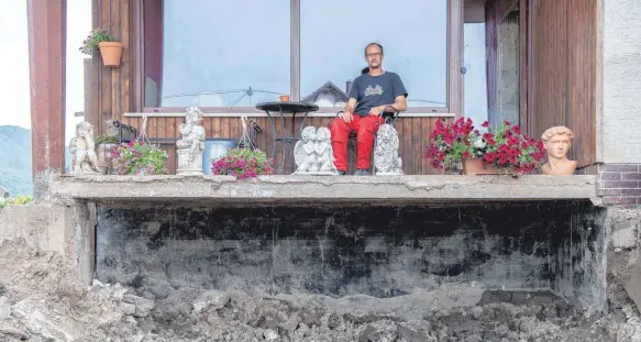  ?? FOTO: BORIS ROESSLER/DPA ?? Daniel Schmitz sitzt auf dem Balkon seiner durch die Flut zerstörten Wohnung im rheinland-pfälzische­n Insul. Vom einst liebevoll gestaltete­n Garten ist nichts mehr übrig geblieben.