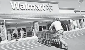  ?? JOE RAEDLE, GETTY IMAGES ?? Walmart employee Yurdin Velazquez returns grocery carts to a store in Miami. Walmart is the largest grocery retailer in the United States and is more than three times bigger than Amazon, based on revenue.