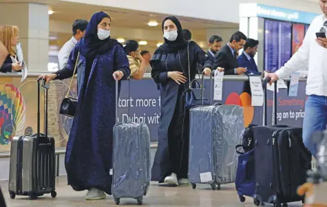  ?? Reuters ?? Travellers wear masks as they arrive at Dubai Internatio­nal Airport. All those coming into the emirate are being screened by discreet, non-contact thermal cameras.