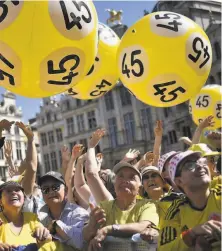  ?? Marco Bertorello / AFP / Getty Images ?? Fans dressed in yellow play with yellow balloons that honor Merckx in Grote Markt Square in Brussels on Thursday.