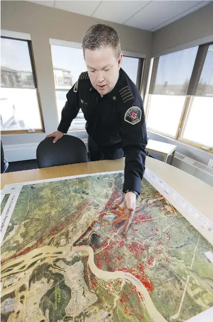  ?? IAN KUCERAK ?? Regional Municipali­ty of Wood Buffalo fire Chief Jody Butz, looking at a map of how the wildfire spread through Fort McMurray and forced people to evacuate on May 3, 2016, reflects prior to the anniversar­y on how the desperate fight against Fire 9...