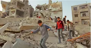  ?? AFP ?? Syrian children walk above the rubble of destroyed buildings in Eastern Ghouta. —