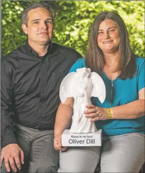  ??  ?? The Dills pose for a portrait with a memorial angel in honor of son Oliver that sits outside their home.