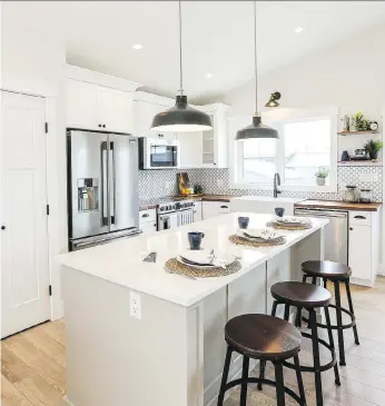  ??  ?? A walnut butcher-block countertop and walnut floating shelves add warmth to the white Shaker-style cabinetry and white quartz-topped island.