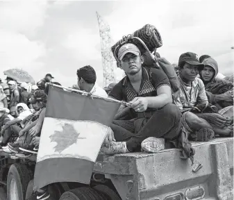  ?? Rebecca Blackwell / Associated Press ?? Honduran migrant Fernando Najar Guillen, 22, carries a handmade Canadian flag as he rides on the back of a flatbed truck with other Central Americans outside Juchitan in Oaxaca state, Mexico.