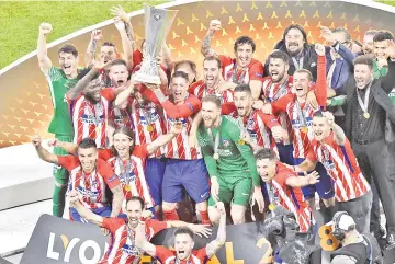  ??  ?? Atletico Madrid’s forward Fernando Torres holds the trophy past teammates after winning the UEFA Europa League final football match between Olympique de Marseille and Club Atletico de Madrid at the Parc OL stadium in Decines-Charpieu, near Lyon. — AFP...