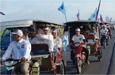  ?? —AFP ?? PHNOM PENH: Supporters of Cambodia National Rescue Party (CNRP) sit on Tuk-Tuks as they travel along a street during the Commune Election Campaign in Phnom Penh yesterday.