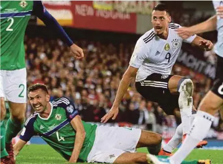  ?? AFP PIC ?? Germany striker Sandro Wagner (right) scores as Northern Ireland defender Gareth Mcauley looks on during their World Cup qualifying match at Windsor Park in Belfast on Thursday.