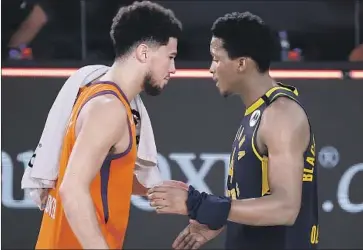  ?? Kevin C. Cox Getty Images ?? DEVIN BOOKER, right, of the Suns meets with the Pacers’ Victor Oladipo after their game. Phoenix has won all four restart games and Booker has been a big reason. “It’s everything I could ask for,” he says.