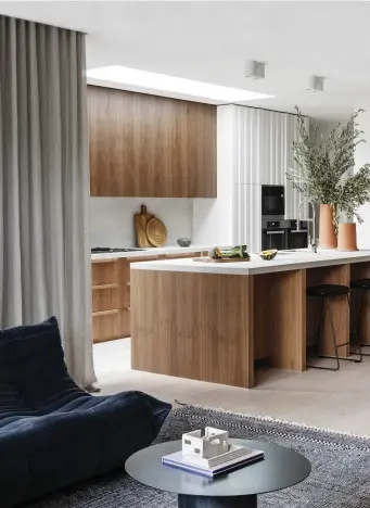  ??  ?? The living and kitchen areas are cocooned in refined joinery, characteri­sed by seamless vertical lines
