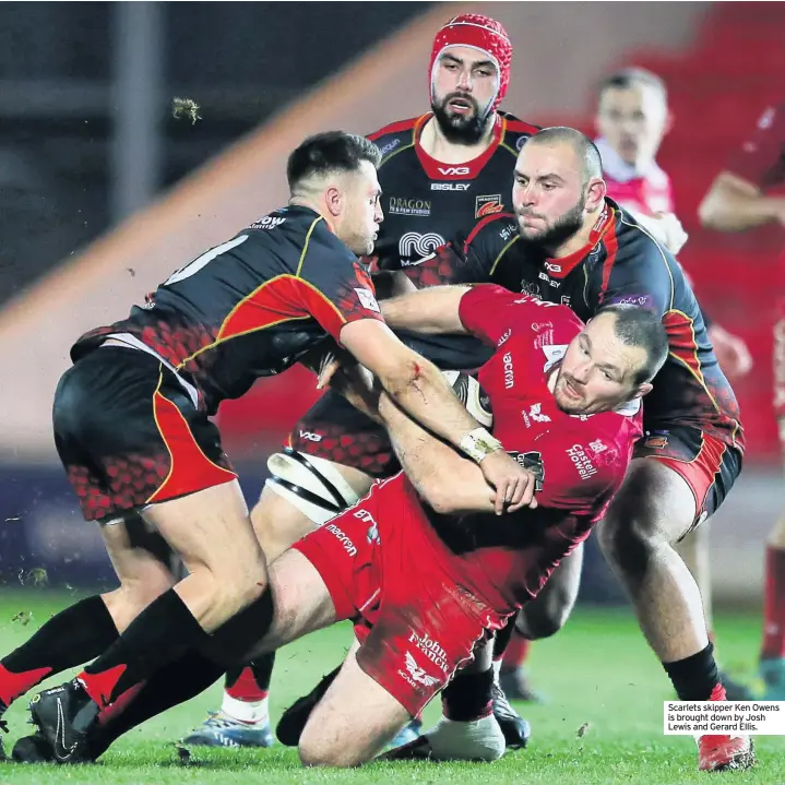  ??  ?? Scarlets skipper Ken Owens is brought down by Josh Lewis and Gerard Ellis.