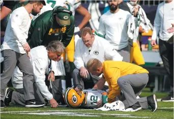  ??  ?? Le quart des Packers de Green Bay, Aaron Rodgers (12), est entouré des soigneurs de l’équipe. - Associated Press: Bruce Kluckhohn
