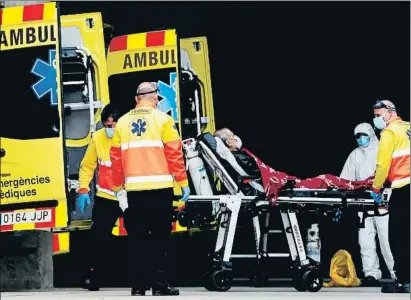  ?? TONI ALBIR / EFE ?? Personal sanitario con un paciente en camilla en la entrada de urgencias del hospital de Bellvitge