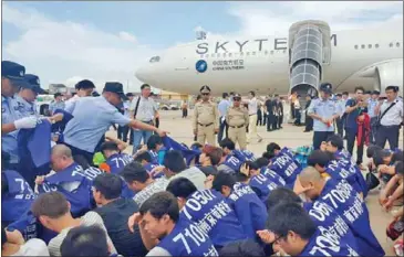  ?? PHOTO SUPPLIED ?? Chinese nationals sit on the tarmac at the Phnom Penh Internatio­nal Airport on Monday before being deported for their involvemen­t in a VOIP scam.