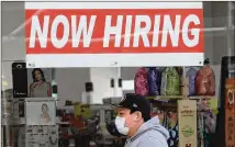  ?? AP ?? A man wearing a mask walks under a hiring sign at a CVS Pharmacy in San Francisco. A report released Tuesday adds to a body of forecasts suggesting the U.S. could experience a POST-COVID-19 boom.