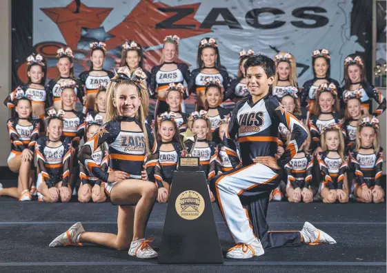  ?? Picture: JERAD WILLIAMS ?? Poppy Watkin, 8, and Matthew Hing, 13, in front of the ZACS Allstars cheer team which claimed six gold at a national competitio­n.