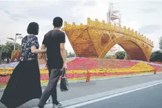  ??  ?? People walk past the installati­on “Golden Bridge on Silk Road” by artist Shu Yong set up ahead of the Belt and Road Forum in Beijing, China. -- Reuters photo