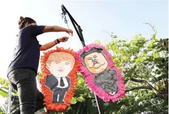  ??  ?? CASHING IN – A Mexican restaurant in Singapore displays piñatas with the caricature­s of US President Donald Trump and North Korean leader Kim Jong Un ahead of their summit on June 12. (AP)