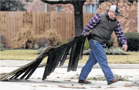  ?? Jason Fochtman / Staff photograph­er ?? In Spring, Scott Roy carries part of his fence that blew across the street into a nearby yard after overnight thundersto­rms damaged his garage, but the Houston area was spared the brunt of the deadly storms that have killed at least 11.