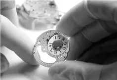  ??  ?? An employee handles the date wheel of a Lange 1 luxury wristwatch during an assembly.