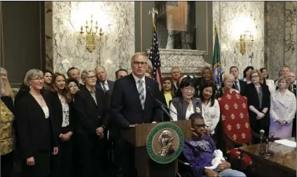  ??  ?? Gov. Jay Inslee (at podium) speaks before signing a measure that makes Washington the first state in the nation to establish a program to help offset the costs of long-term care, on Monday, in Olympia, Wash. AP PHOTO/RACHEL LA CORTE