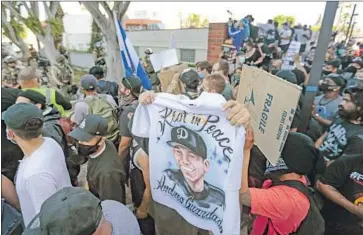  ?? Jason Armond Los Angeles Times ?? AN IMAGE of Andres Guardado is held aloft as people rally outside the Compton’s sheriff’s office Sunday. Guardado was shot by a deputy last week, and county supervisor­s have voted for more oversight of the case.