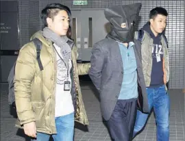  ?? Associated Press ?? DEYUN SHI, 44, center, uncle of Anthony and William and the suspect in their slayings, is escorted by officers as he is taken into custody Sunday in Hong Kong.