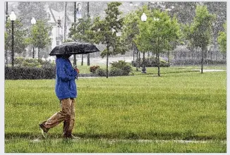  ?? MARSHALL GORBY / STAFF ?? A pedestrian tries to stay dry while walking along Main Street in Dayton on Tuesday. Rain is to continue through most of the week.