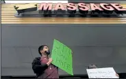  ?? Elijah Nouvelage / Getty Images ?? Jesus Estrella holds a sign of solidarity outside Youngs Asian Massage where four people were shot and killed on March 17 in Acworth, Ga.