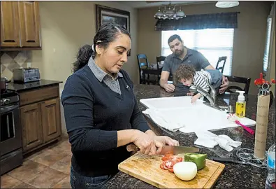  ?? NWA Democrat-Gazette/BEN GOFF ?? Maria Sanabria prepares a meal Thursday as her husband, Jose, plays with their daughter, Elena, in Centerton. Jose Sanabria said “it’s hard to really give an answer” when he was asked about his status as federal protection­s for Salvadoran­s are set to...