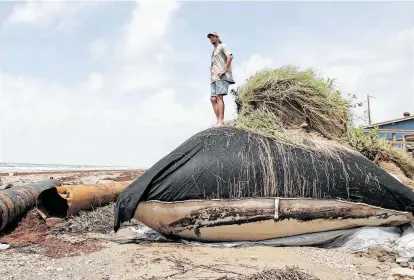  ?? Chronicle file photo ?? Chuck Hale surveys a damaged geotube at Rollover Pass on the Bolivar Peninsula after Hurricane Claudette battered the coast in 2003. A new plan to bolster gulf communitie­s from storm surge calls for a shift to natural sand dunes.