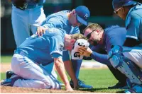  ?? REED HOFFMANN/AP ?? Kansas City Royals pitcher Ryan Yarbrough is tended to by training staff and Royals manager Matt Quatraro, top, after being hit by a line drive Sunday.