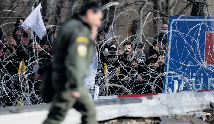  ?? Foto: Giannis Papanikos/ap/tt ?? Migranter bakom en avspärrnin­g nära den grekisk-turkiska gränsen i Kastanies.