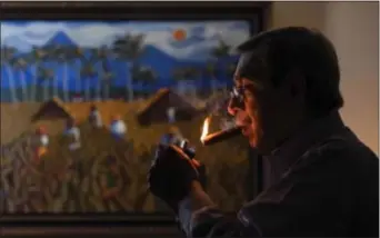  ?? DENNIS M. RIVERA PICHARDO — BLOOMBERG VIA AP ?? Manuel Quesada, owner of Quesada Cigars, lights a cigar inside his office in Santiago de los Caballeros, Dominican Republic, on. The Quesada family, Cuban tobacco exiles operating out of the Dominican Republic, prepare to confront their communist...