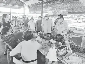  ??  ?? TINJAU: Lee (kanan) Yii berbual-bual dengan penjaja semasa pelancaran kaunter bergerak pendaftara­n vaksin di Tamu Morsjaya semalam.