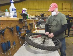  ?? Flip Putthoff/NWA Democrat-Gazette ?? Steve Carter repairs a flat tire in January 2022 at the Pedal It Forward workshop in Rogers, where volunteers fix up donated bicycles they provide to anyone who needs a bike. Riders can take measures to prevent flats and carry items on their bikes to fix a flat if needed.