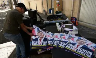  ?? (Photo AFP) ?? Un militant du mouvement La France Insoumise (LFI) s’empare des affiches de campagne du leader Jean-Luc Melenchon, prêtes pour les législativ­es des 12 et 19 juin prochains.