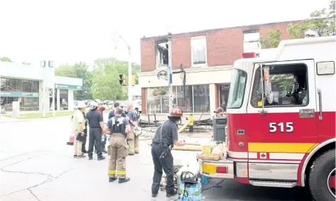  ?? GRANT LAFLECHE/POSTMEDIA NEWS ?? Grimsby firefighte­rs, Ontario Fire Marshall investigat­ors and town officials survey the damage to the building at the corner of Main and Elm streets in Grimsby Friday morning. The building, which housed three businesses and one apartment, was destroyed...