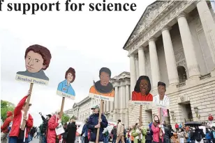  ??  ?? People hold signs of pioneering women in science in front the US Environmen­tal Protection Agency during the March for Science in Washington on April 22, 2017. Scientists, students and research advocates rallied from the Brandenbur­g Gate to the...