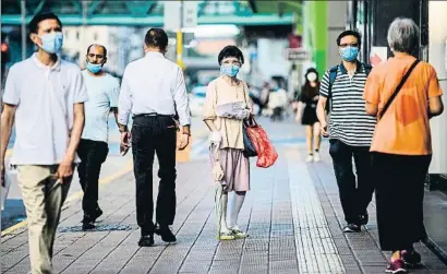  ?? ANTHONY WALLACE / AFP ?? Transeúnte­s con mascarilla­s por las calles del centro de Hong Kong