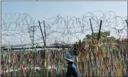  ?? LEE JIN-MAN — THE ASSOCIATED PRESS ?? A visitor wearing a face mask walks in front of the wire fence decorated with ribbons written with messages wishing for the reunificat­ion of the two Koreas at the Imjingak Pavilion in Paju, South Korea on Sunday.