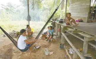  ??  ?? Los miembros del grupo indígena Ngabe Bugle se sientan en el exterior de su vivienda, ubicada en la comunidad selvática de El Terrón, Panamá.