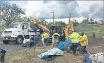  ?? PHOTO BY AARON DAVIS ?? Homeless people look on as workers use a backhoe and dump truck to remove all remaining tents and items from an encampment on McElheney Road in Antioch on Monday.